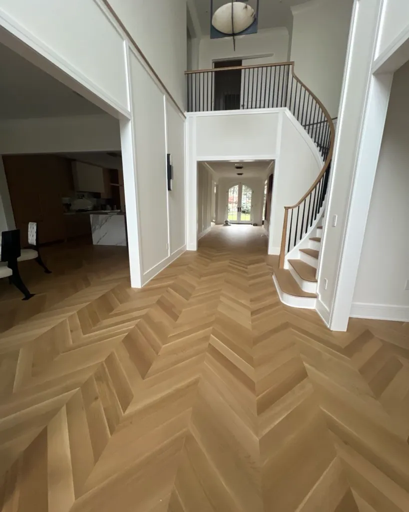 Grand entryway with herringbone hardwood pattern and curved staircase