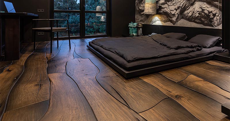 Dramatic bedroom with dark live-edge wide-plank hardwood floors