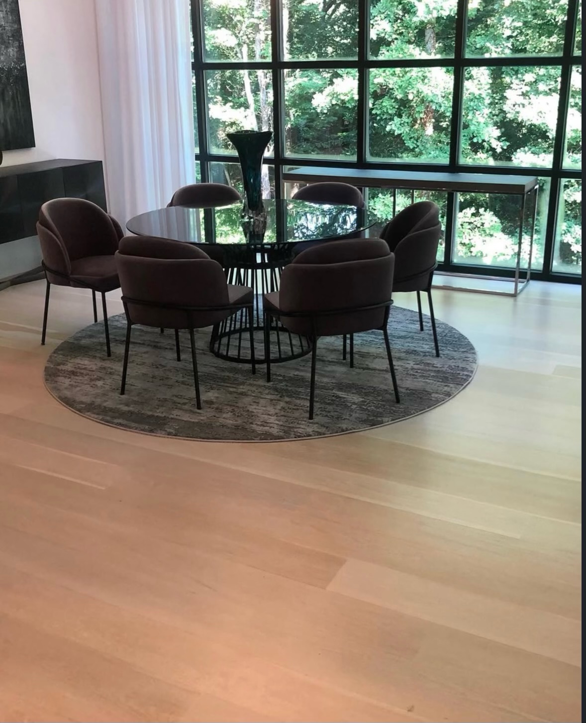 Modern dining room with light wide-plank hardwood floors and floor-to-ceiling windows