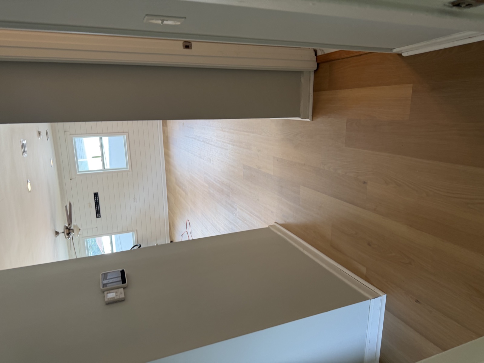 Light natural oak hardwood flooring running through hallway into open living space with shiplap accent wall