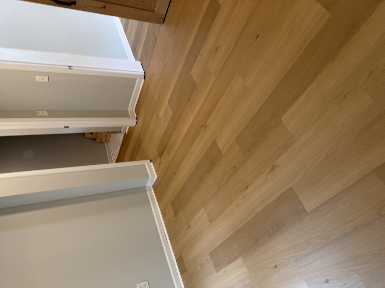 Light natural oak wide-plank hardwood flooring installed in residential room with multiple doorways