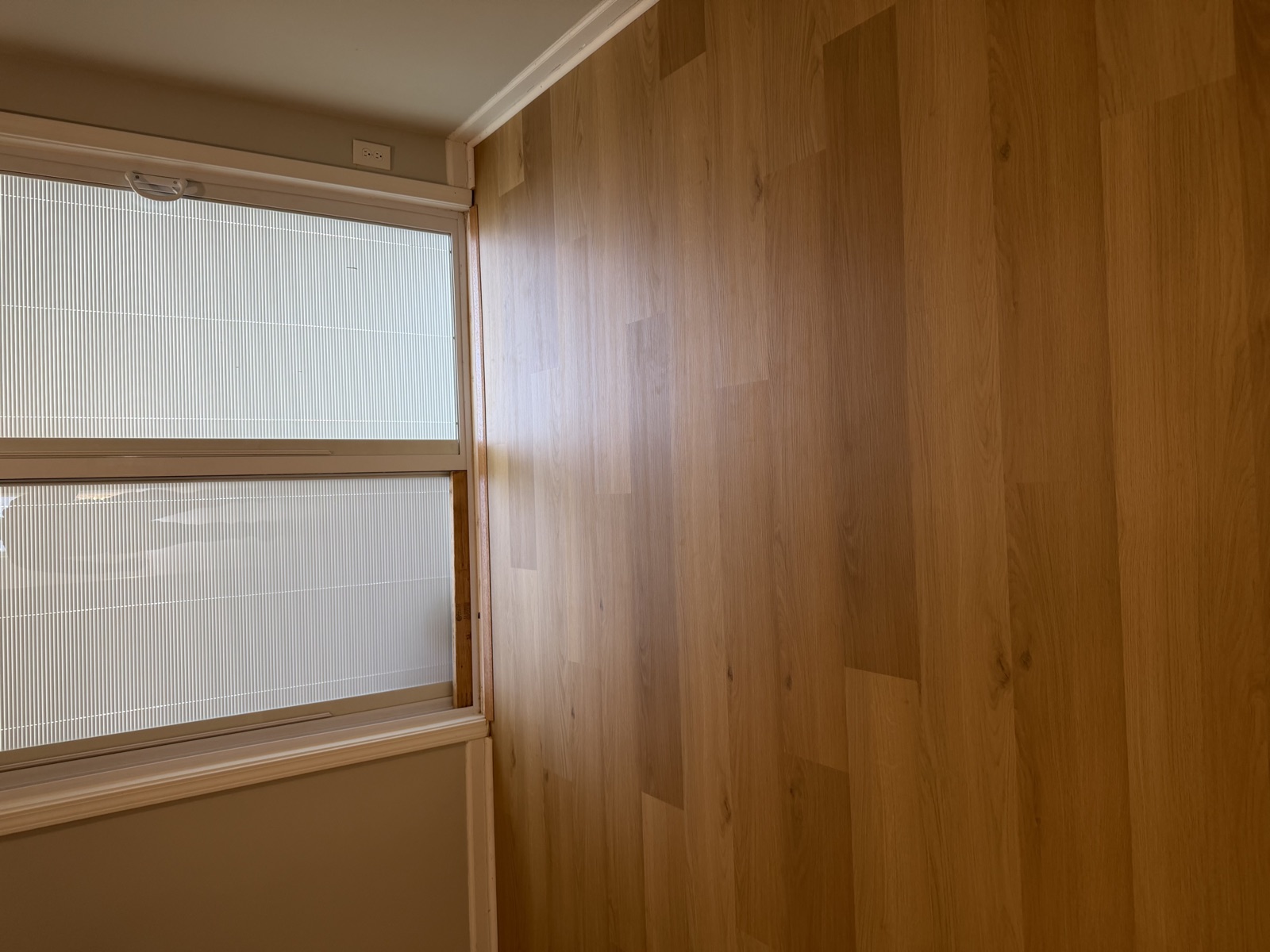 Light natural oak wide-plank hardwood flooring with warm natural light from sliding glass door