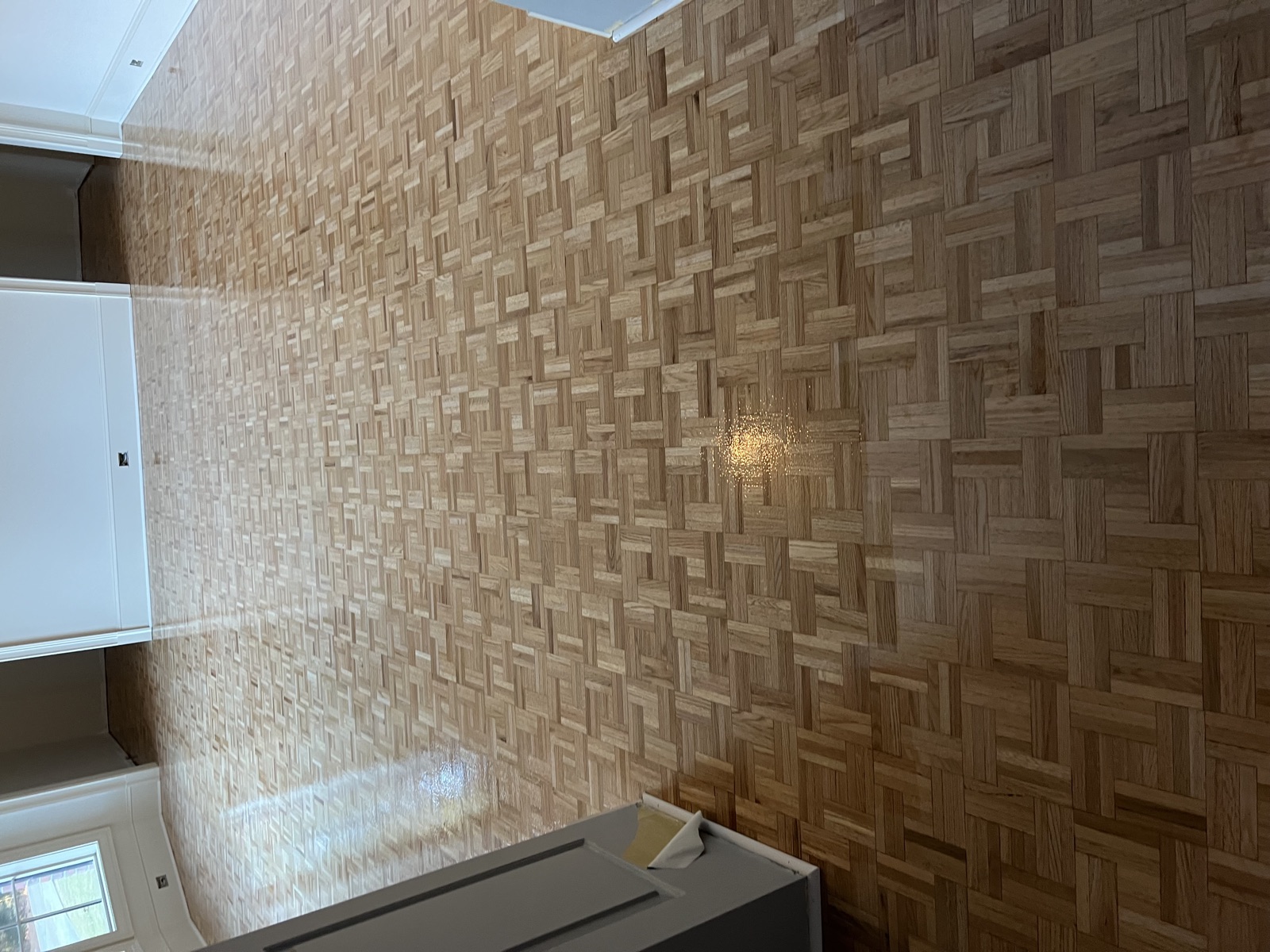 Basket-weave parquet hardwood flooring with freshly applied high-gloss finish in large open room