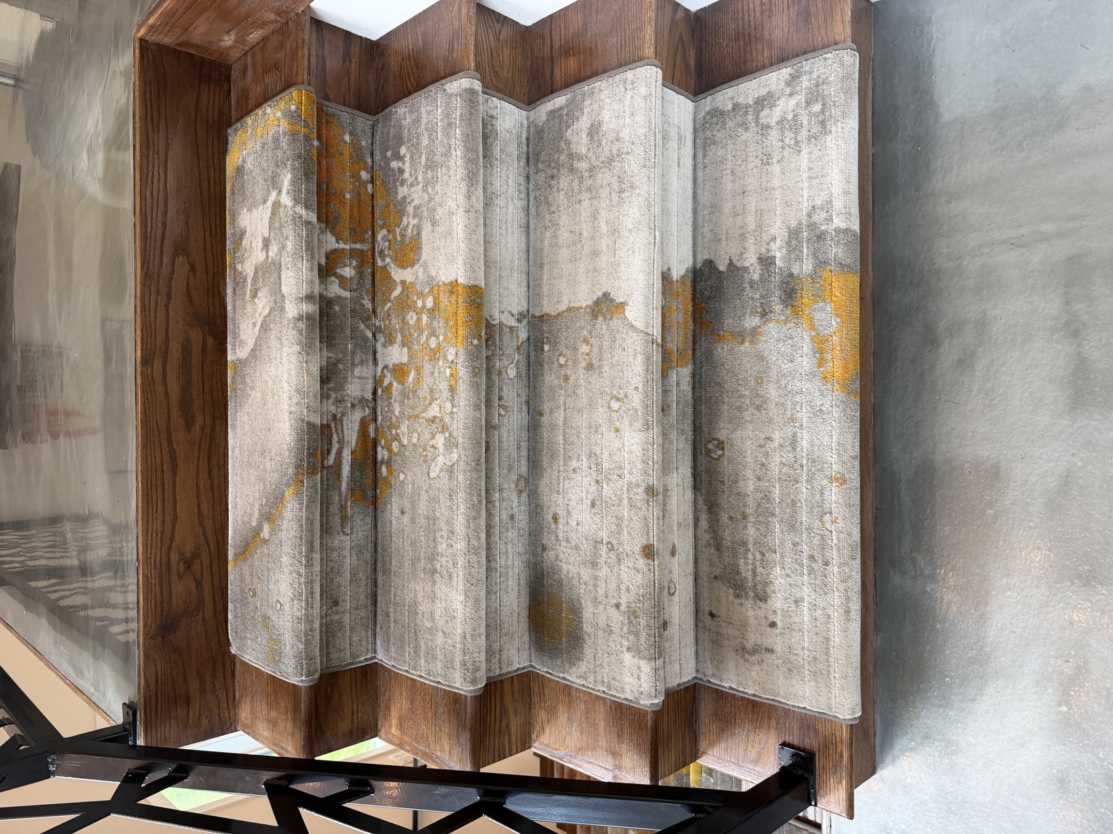 Close-up detail of abstract carpet stair runners with cream, gray, and gold pattern on oak stair treads