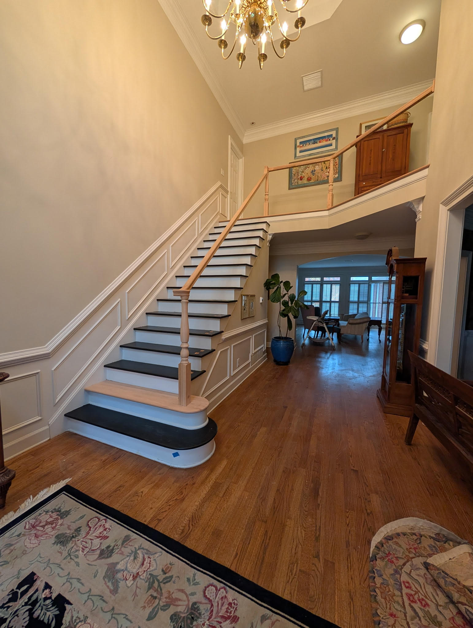 Grand two-story foyer with staircase treads and warm oak hardwood floors