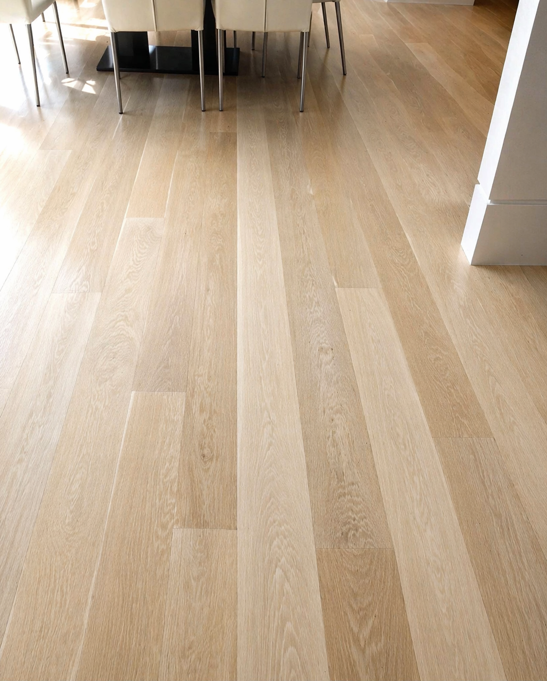 Close-up of light oak wide-plank hardwood flooring in dining space