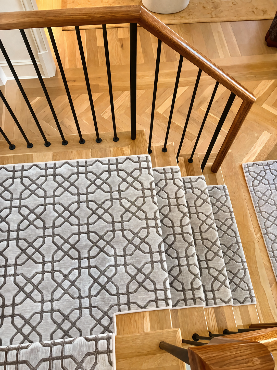 Custom carpet stair runners over herringbone hardwood flooring
